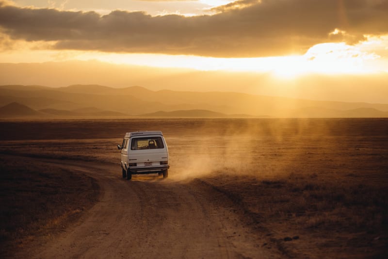 A van on a dusty road at sunset